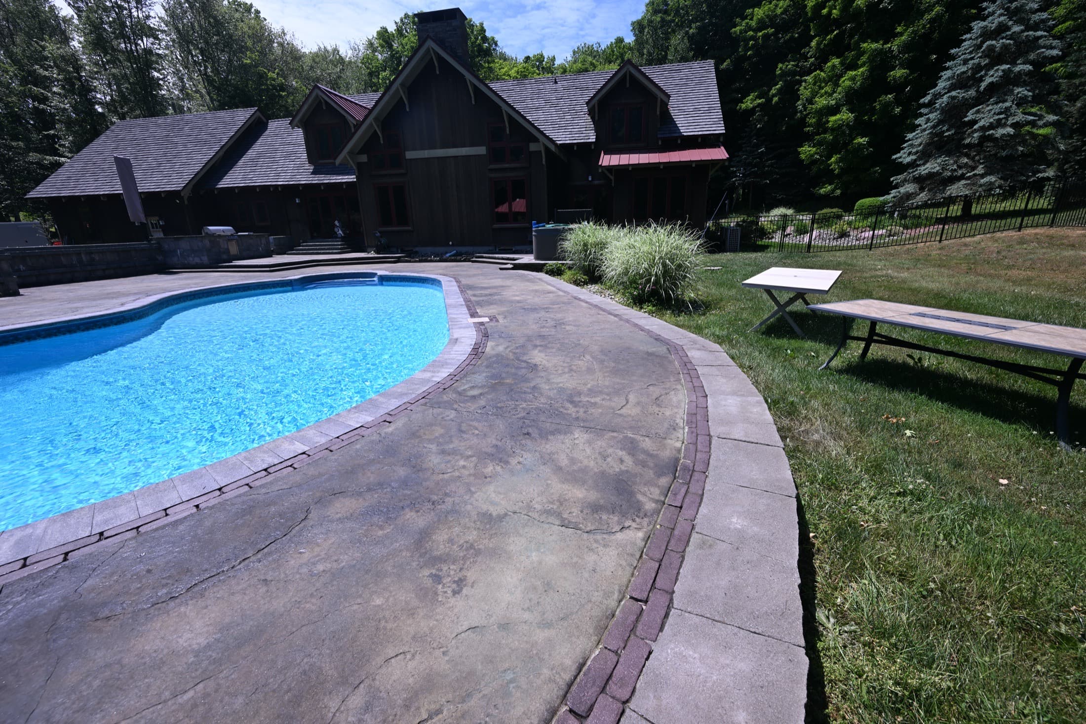 Finished acid-stained pool deck with brick border in Crawford, NY