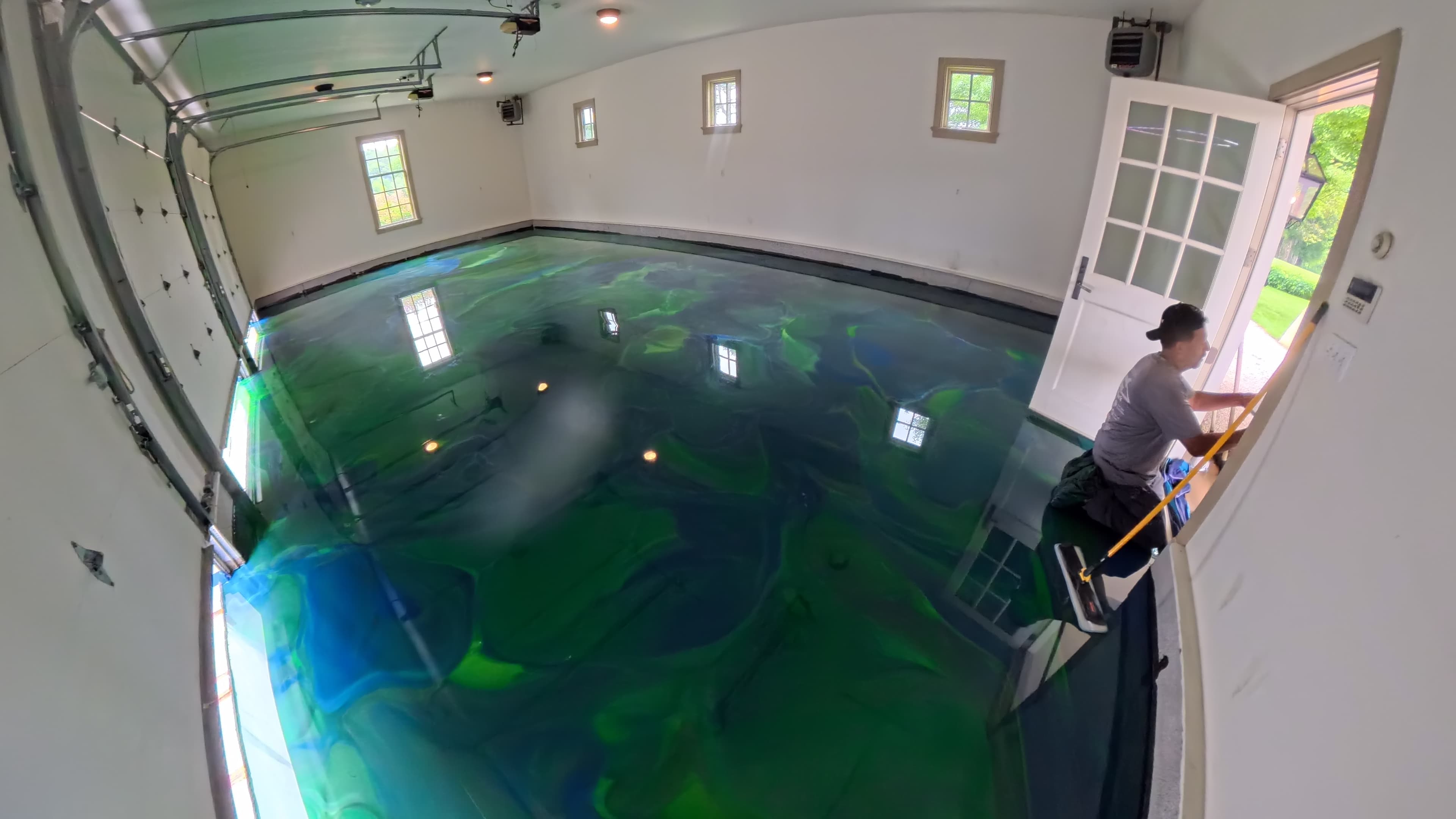 Technician detailing the edges of the metallic epoxy garage floor in Amenia, NY