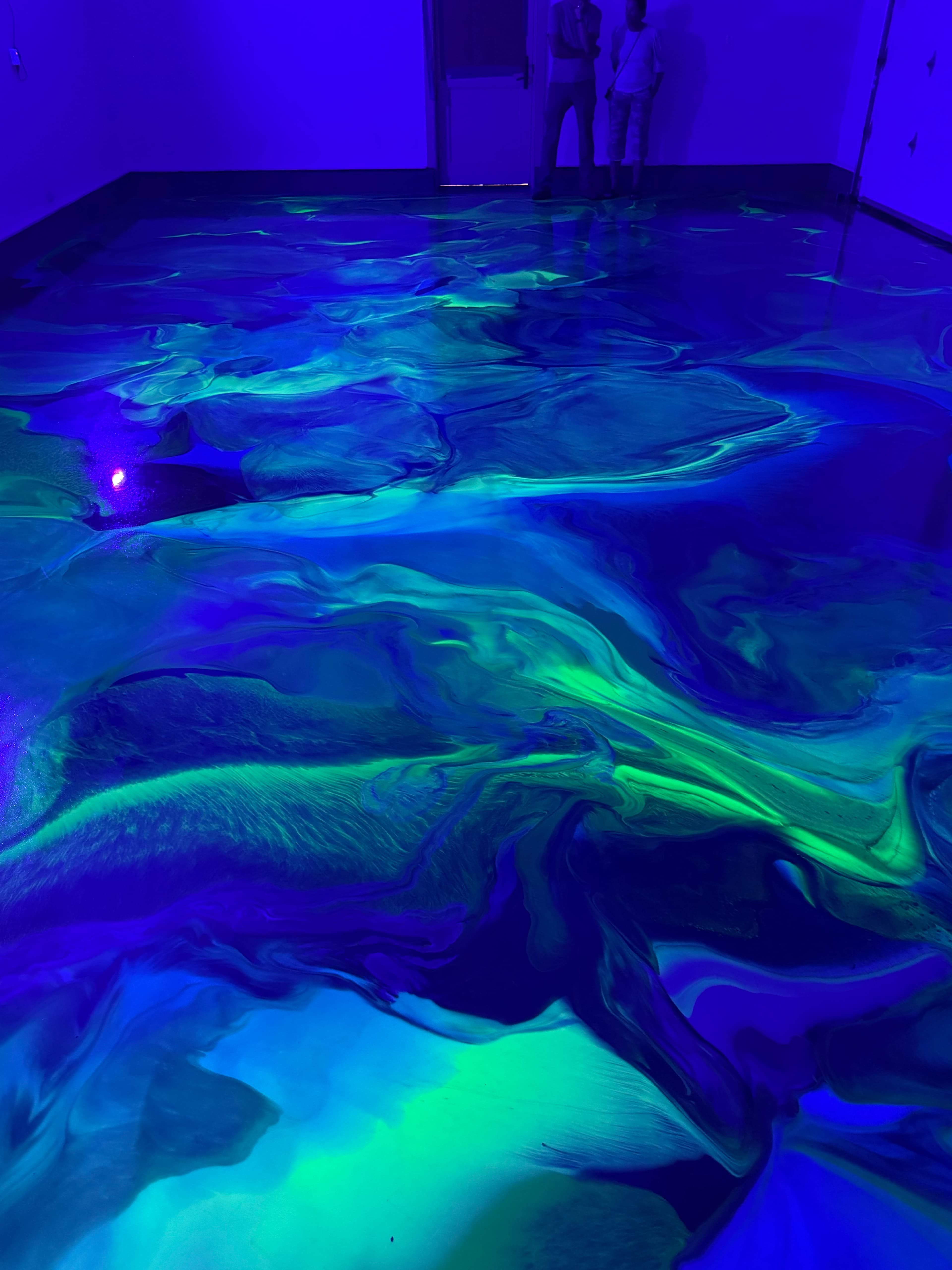 Metallic epoxy garage floor glowing under UV light in Amenia, NY