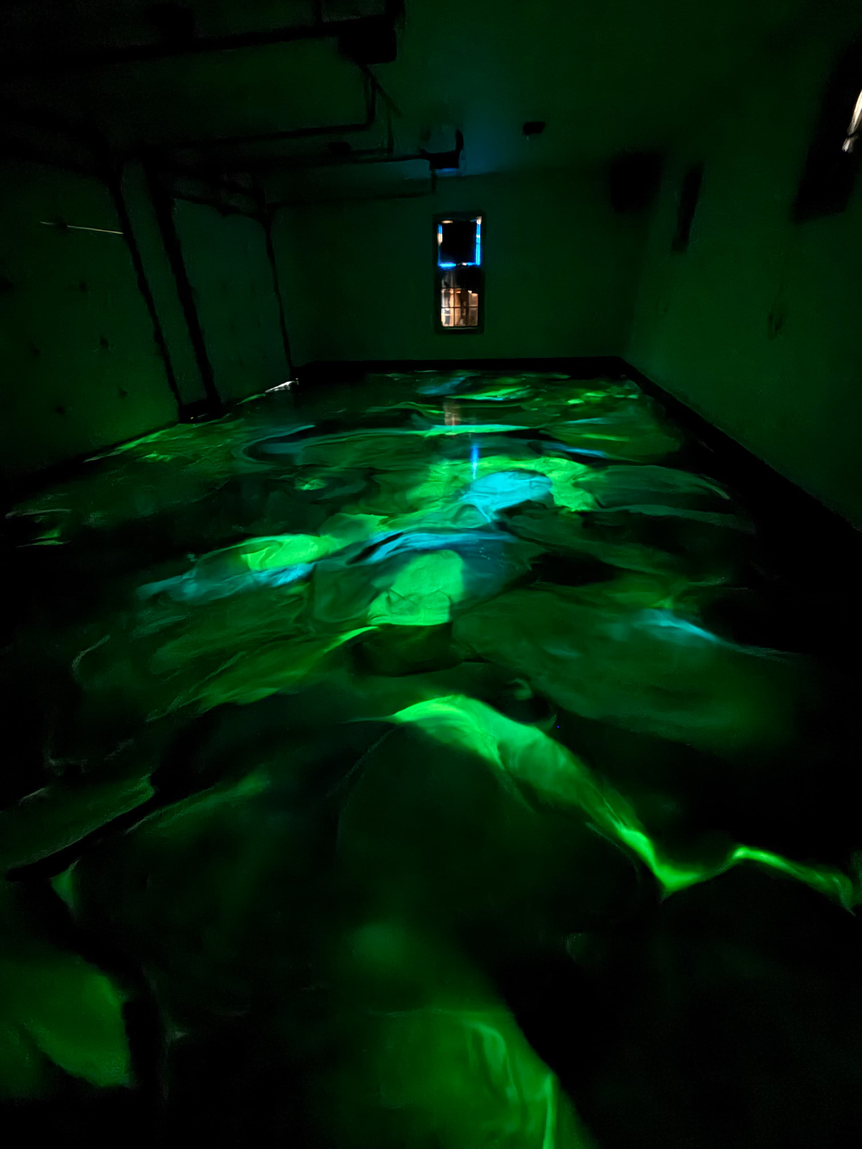 Glow-in-the-dark epoxy garage floor lit up green with the lights off in Amenia, NY